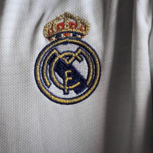 Detailed view of a famous embroidered logo on a white sports jersey fabric.