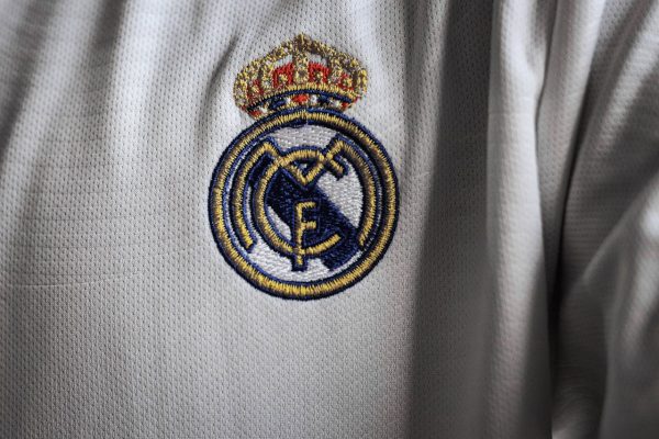 Detailed view of a famous embroidered logo on a white sports jersey fabric.