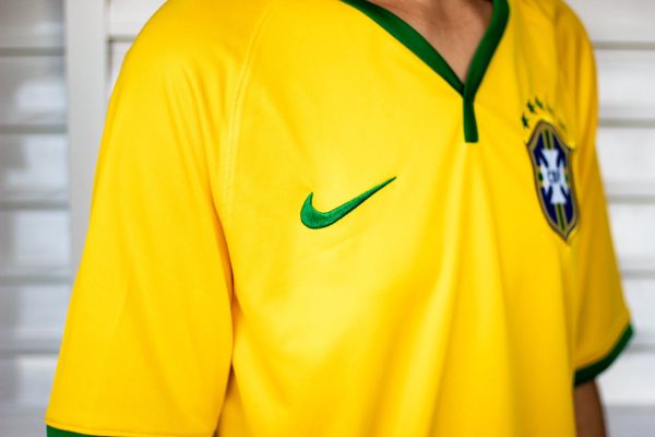 Crop unrecognizable person in bright yellow shirt standing near white stairway for training in sports hall
